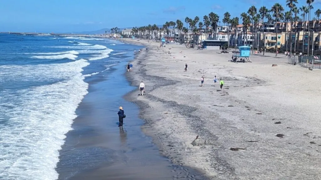 Fotografía de fuertes olas en la costa de California con cielo despejado y advertencia de seguridad marítima