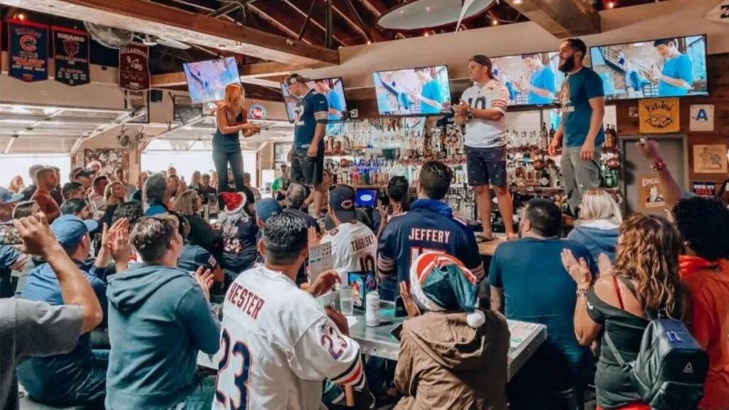 Aficionados en un NFL Team Bar en San Diego disfrutando de un juego de fútbol americano con pantallas gigantes y ambiente temático