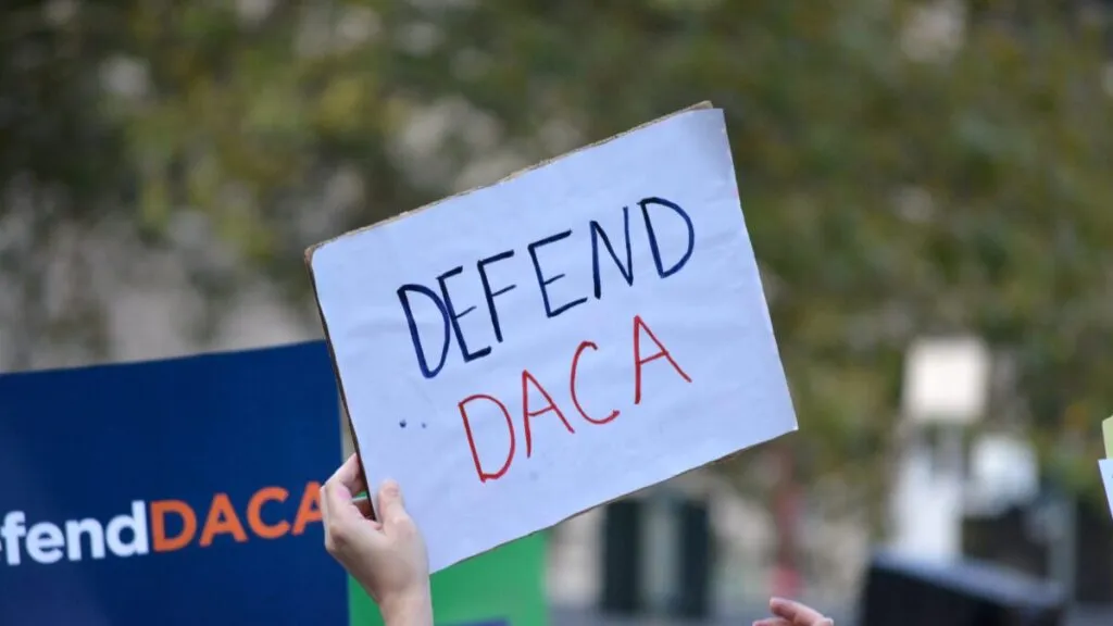 Jóvenes reunidos en San Diego con carteles de apoyo a solicitudes de DACA frente a un edificio gubernamental