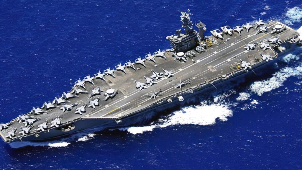 Helicóptero naval MH-60R Sea Hawk volando sobre el océano frente al USS Nimitz