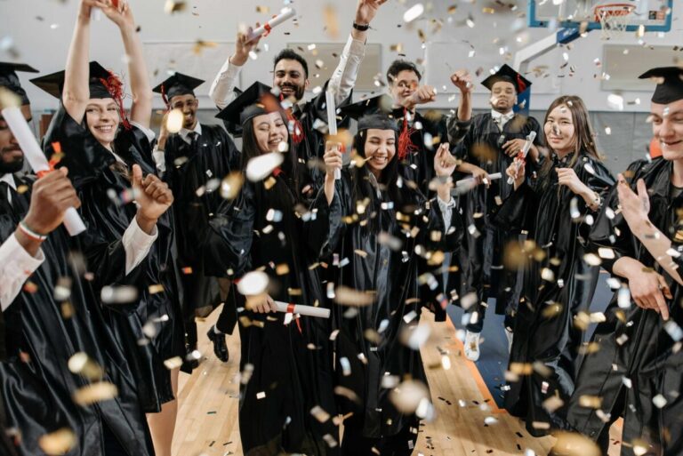 Estudiantes hispanos celebrando la graduación con toga y birrete, reflejando el aumento de la tasa de graduación en San Diego.