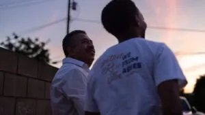 Migrantes latinos caminan con maletas cerca de la frontera, reflejando autodeportación, miedo a redadas y resiliencia comunitaria en California y San Diego