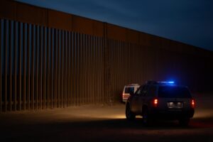 Imagen del muro fronterizo en Otay Mesa, San Diego, con presencia policial y estructura de gran altura, asociada a la caída mortal de una mujer mexicana.