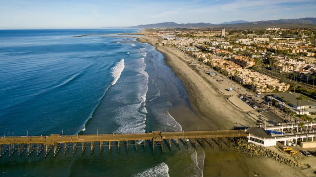 Rescatistas y bomberos de Oceanside ayudan a dos personas tras un velero atrapado en el oleaje frente a Harbor Beach.