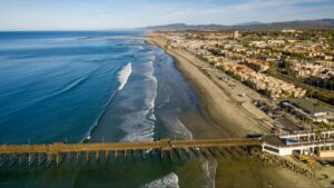 Rescatistas y bomberos de Oceanside ayudan a dos personas tras un velero atrapado en el oleaje frente a Harbor Beach.