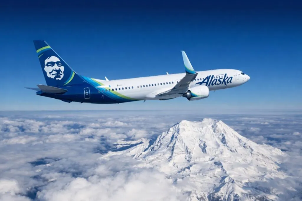 Avión de Alaska Airlines volando sobre montañas nevadas, símbolo de su expansión desde San Diego