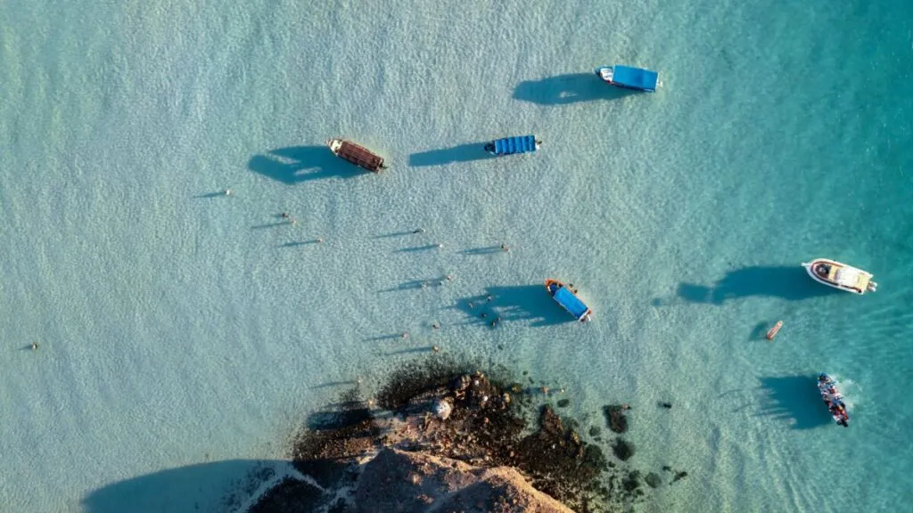 Fotografía aérea de playa mexicana con bandera Blue Flag visible y turistas disfrutando de agua limpia y servicios seguros