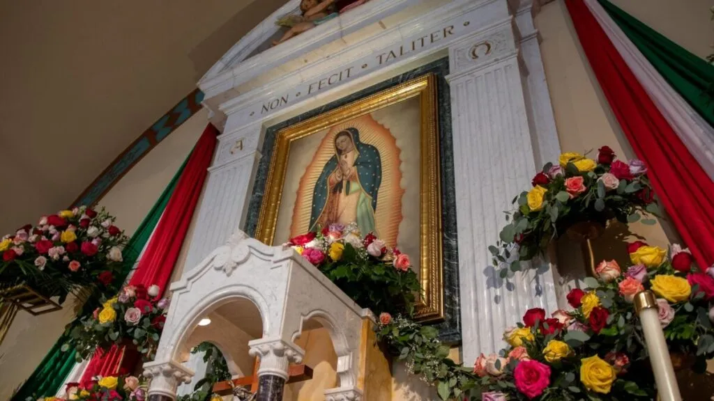 Fotografía editorial emotiva, altar doméstico a la Virgen de Guadalupe, ambiente nocturno cálido, estilo periodístico, sin texto, formato horizontal.