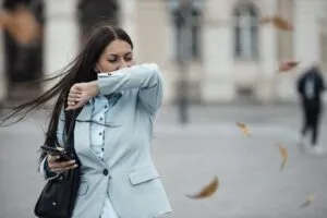 Mujer hispana se cubre al toser en invierno en San Diego, ilustrando aumento de gripe