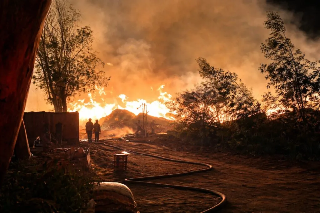 Imagen del incendio en El Refugio, Tijuana, con llamas activas y presencia de bomberos durante la evacuación