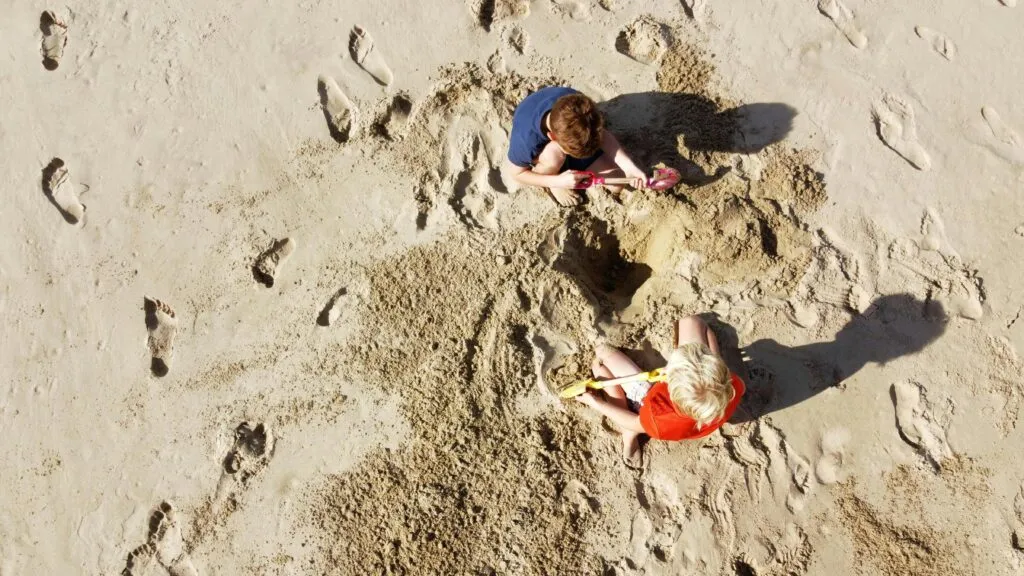 Vista de bañistas disfrutando y respetando la seguridad en la playa de Del Mar con señalización que promueve la prevención de cavar agujeros playa