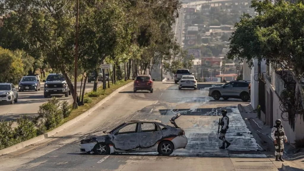 Vehículo incendiado en avenida urbana durante jornada de violencia en Baja California con presencia policial y bloqueos