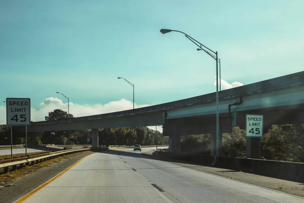 Vista de una calle de San Diego con señal de límites de velocidad reducidos y peatones cruzando, reflejando mejoras en seguridad vial.