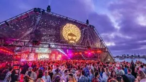 Personas disfrutando el Mustache Bash en Mission Beach con música en vivo, baile y vestimenta inspirada en los años setenta