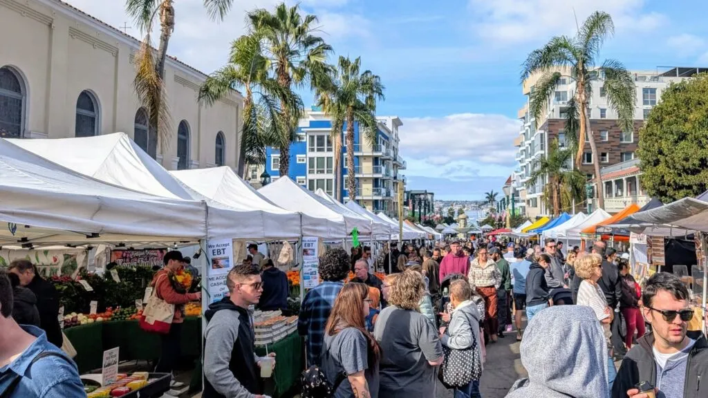 visitantes recorriendo The Little Italy Mercato entre puestos de comida y productos frescos