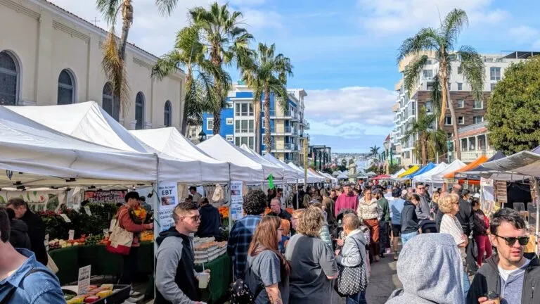 visitantes recorriendo The Little Italy Mercato entre puestos de comida y productos frescos