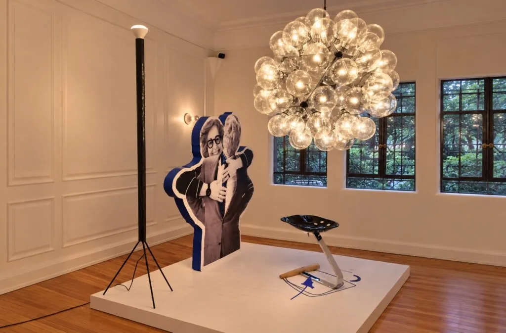 Exposición de diseño italiano dedicada a Achille Castiglioni con muebles, luminarias, fotografías y documentos históricos.