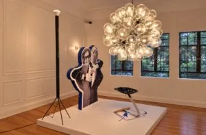 Exposición de diseño italiano dedicada a Achille Castiglioni con muebles, luminarias, fotografías y documentos históricos.
