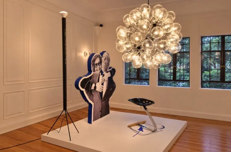 Exposición de diseño italiano dedicada a Achille Castiglioni con muebles, luminarias, fotografías y documentos históricos.